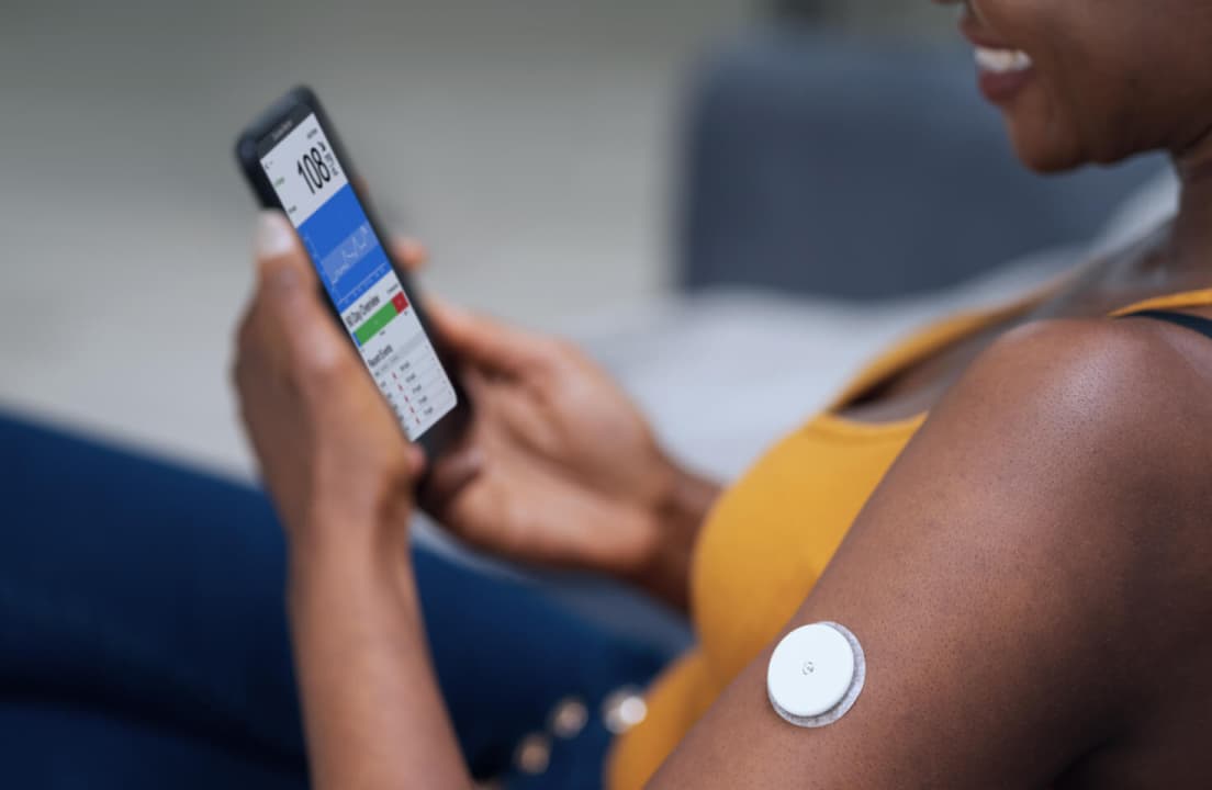 A person comfortably wearing a CGM sensor on their arm while dressed in casual daily attire.