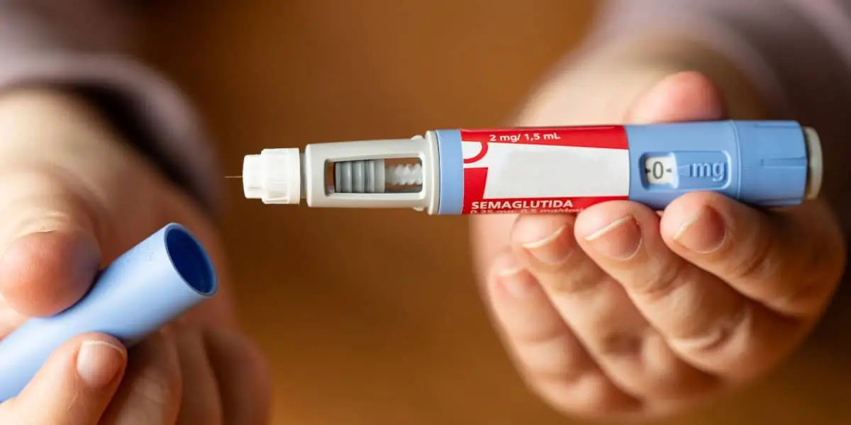 A close-up of a person holding a semaglutide injection pen.