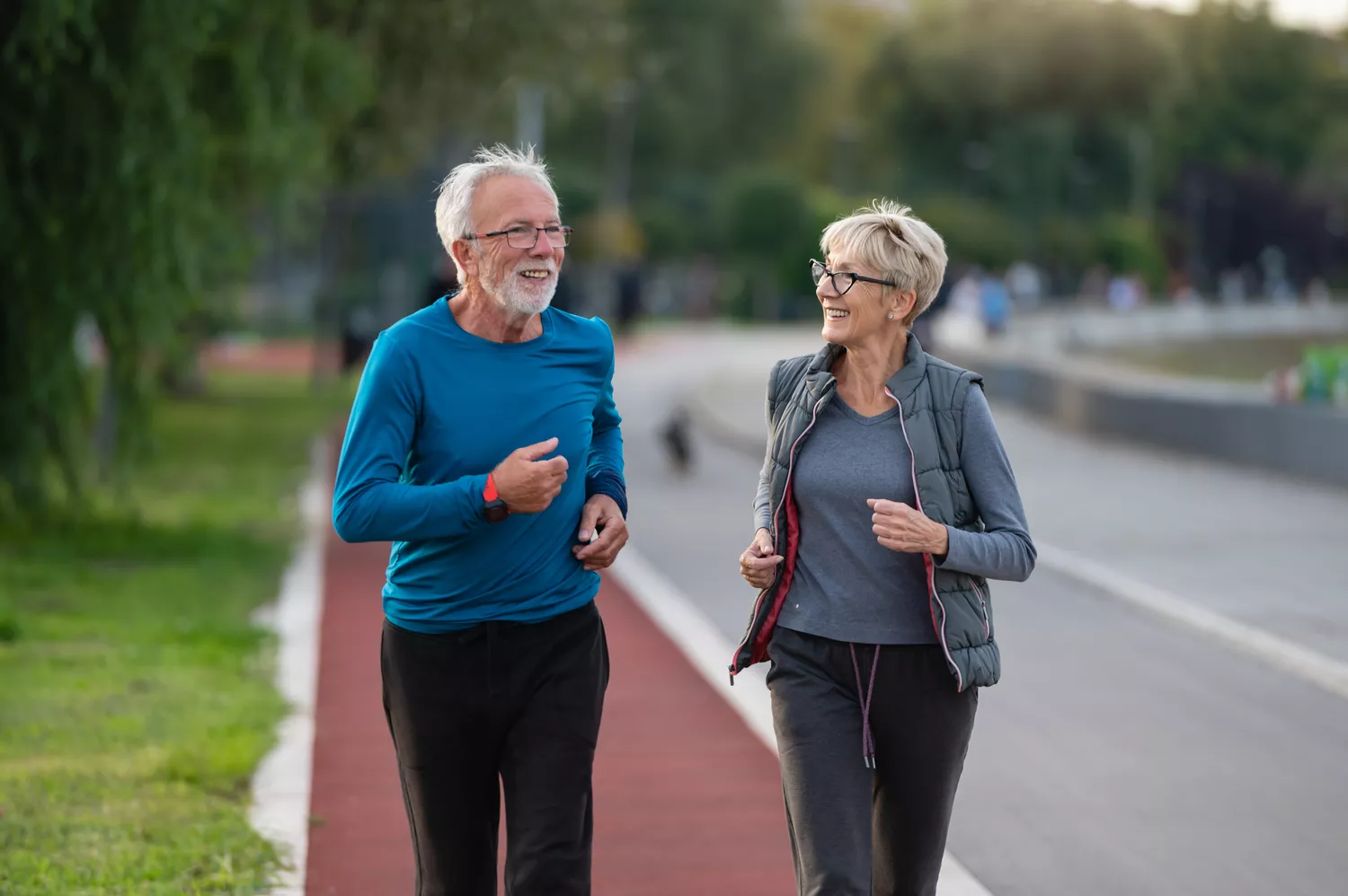An older couple jogging together on an outdoor path.