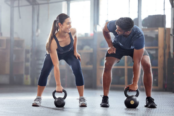 A fitness coach providing technique feedback to a woman performing a squat.