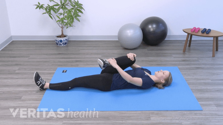A patient performing a supine piriformis stretch with the assistance of a physical therapist.