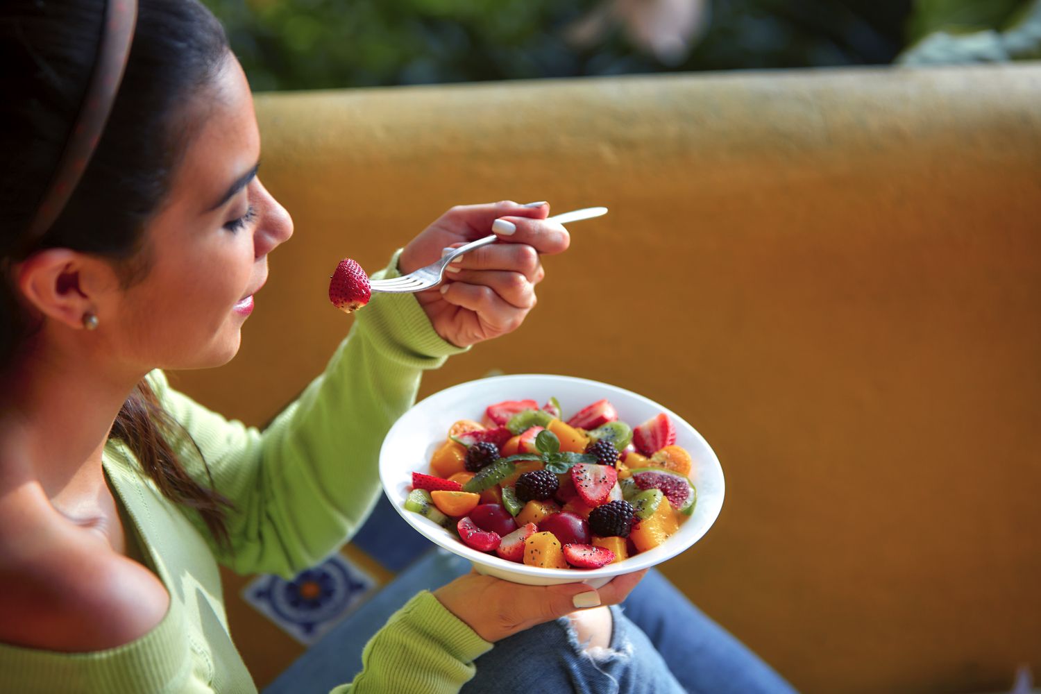 A young woman eating fruit salad outdoors