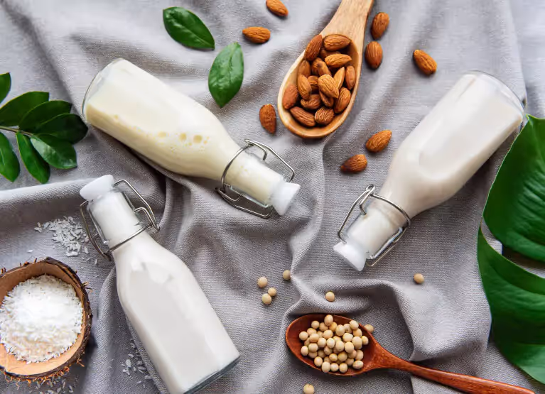Several different brands and types of plant-based milk bottles lined up together.