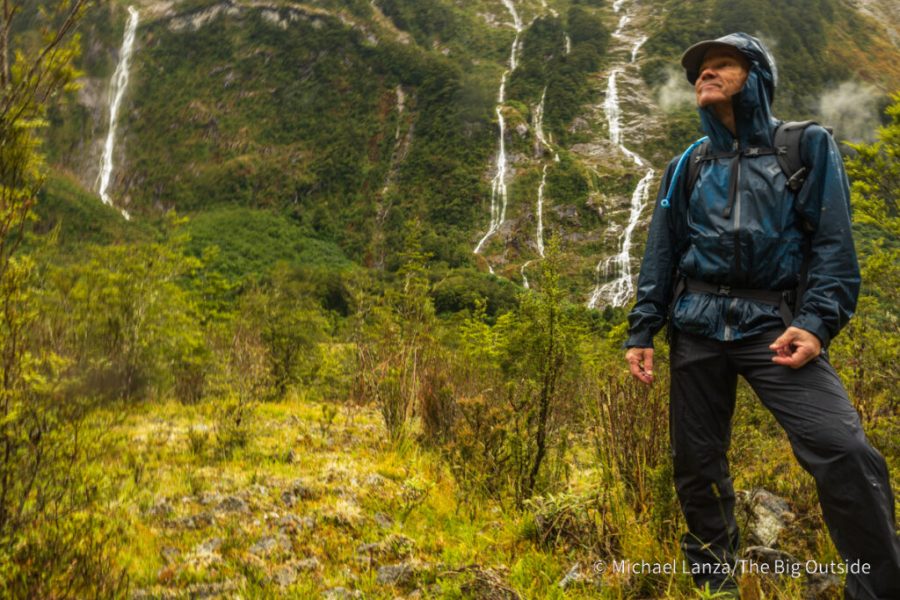 A high-quality waterproof shell jacket being used on a rainy hiking trail.