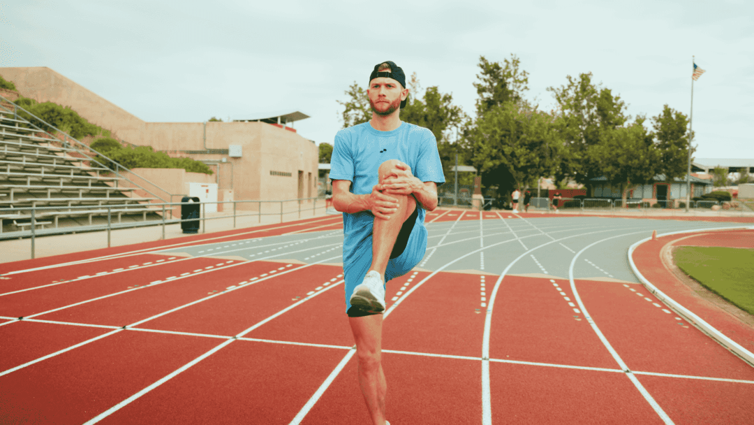 Side view of an athlete performing a focused mobility drill on a mat.