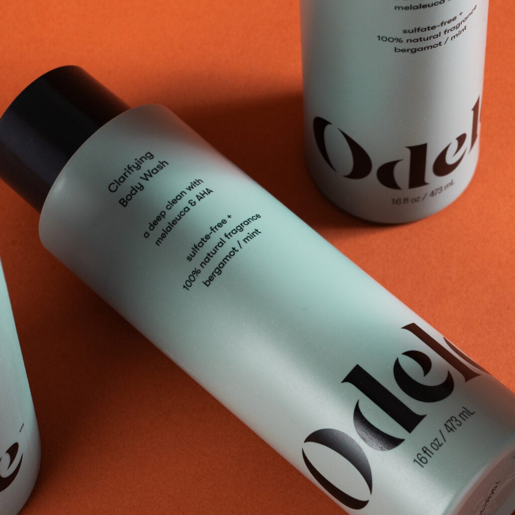 Several bottles of Odele Clarifying Body Wash on a flat surface.