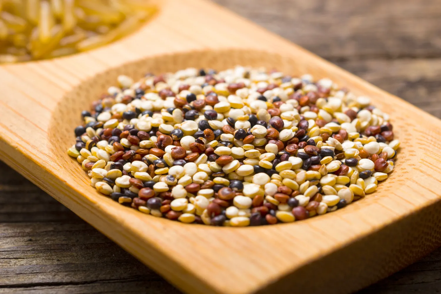 A variety of mixed whole grains scattered on a rustic wooden surface.