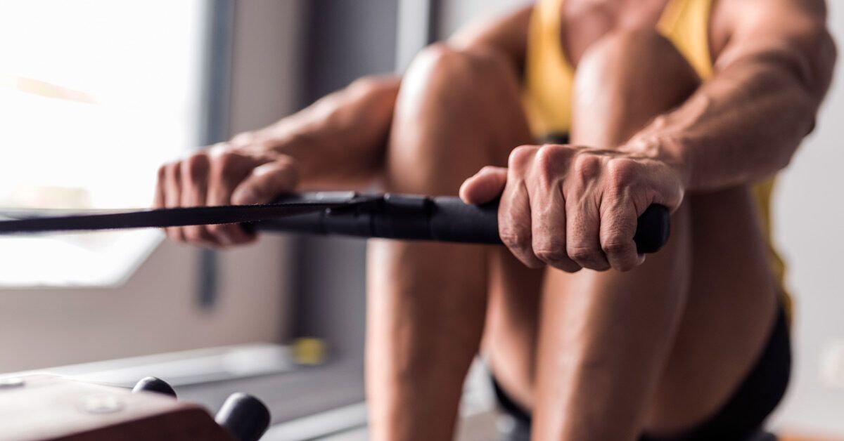A person in a gym using a rowing machine with high intensity.