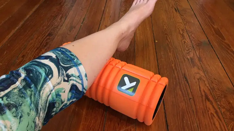 A close-up demonstration of a person using a black TriggerPoint GRID foam roller.