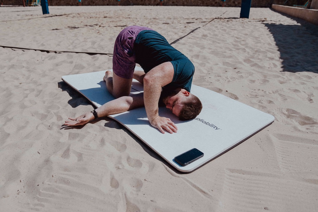 A man performing a seated hamstring and back stretch for recovery.
