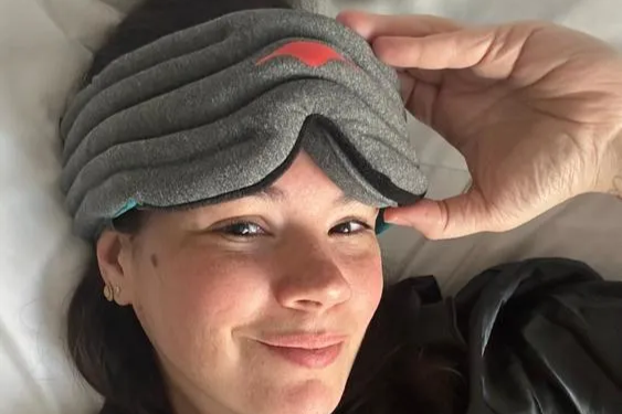 A woman wearing a gray weighted eye mask for relaxation.