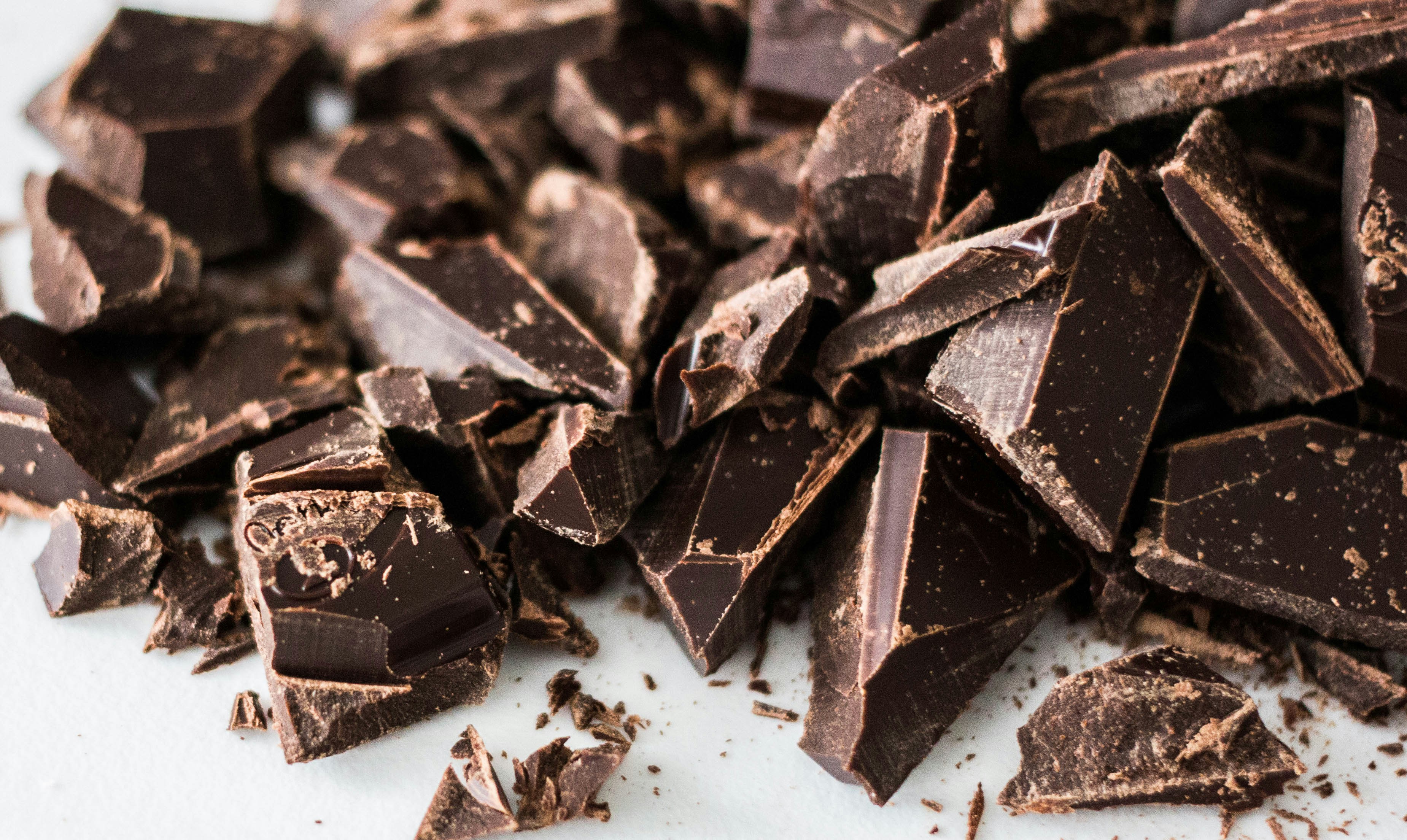 Several pieces of dark chocolate with high cocoa content stacked on a neutral surface.