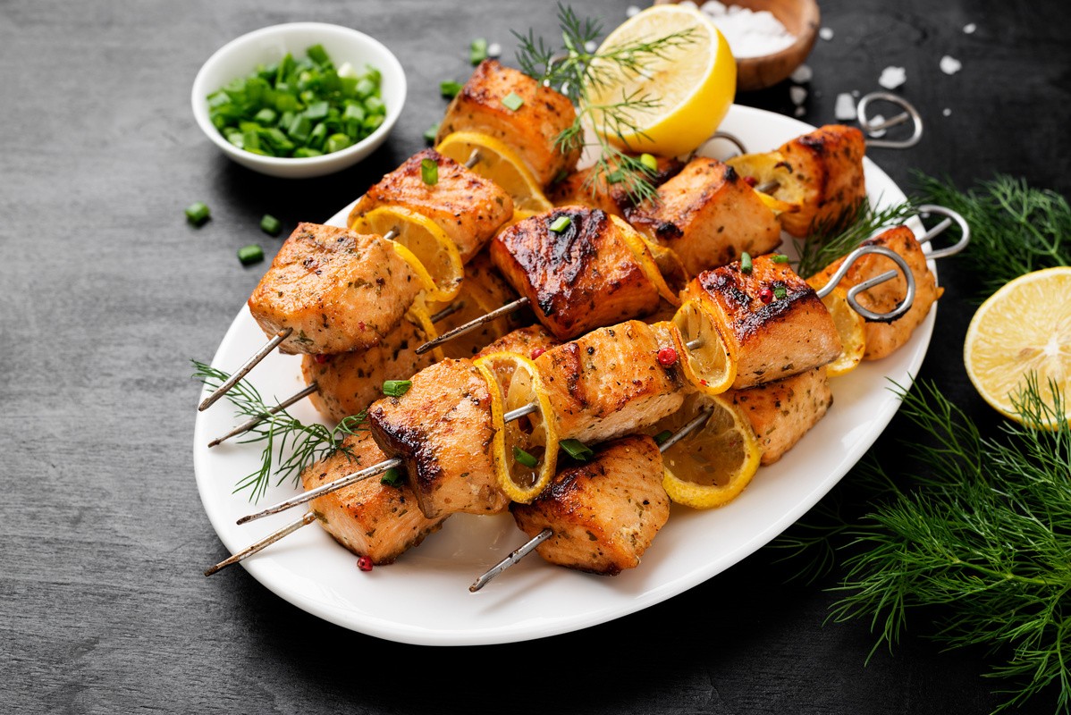 Grilled salmon kabobs with zucchini and bell peppers in a meal prep container.