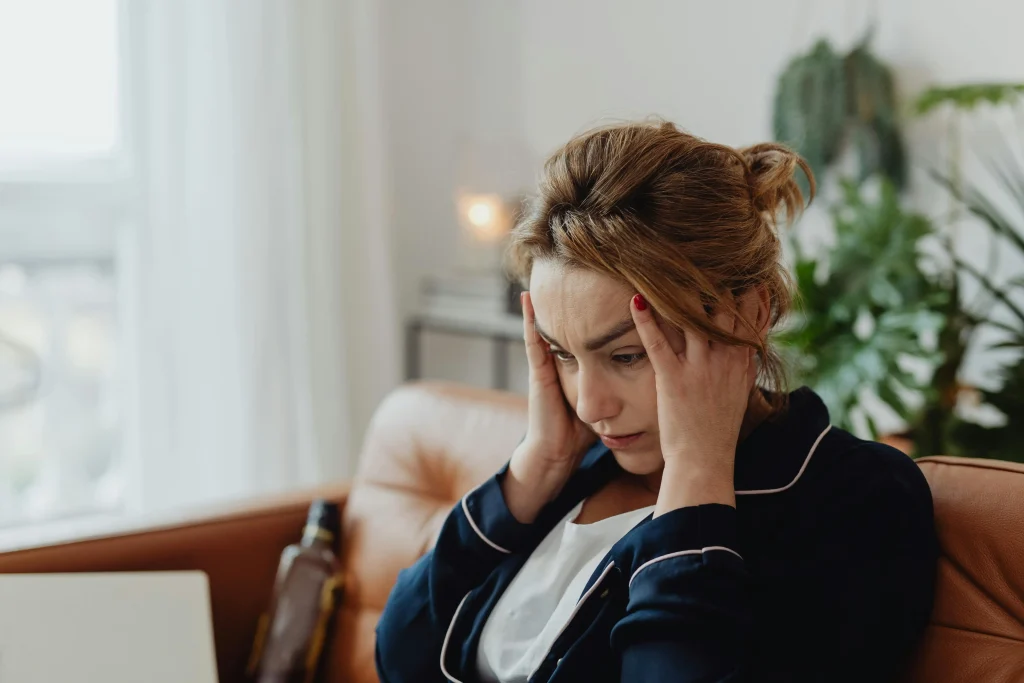 A woman showing signs of emotional distress and frustration with her hands to her head.