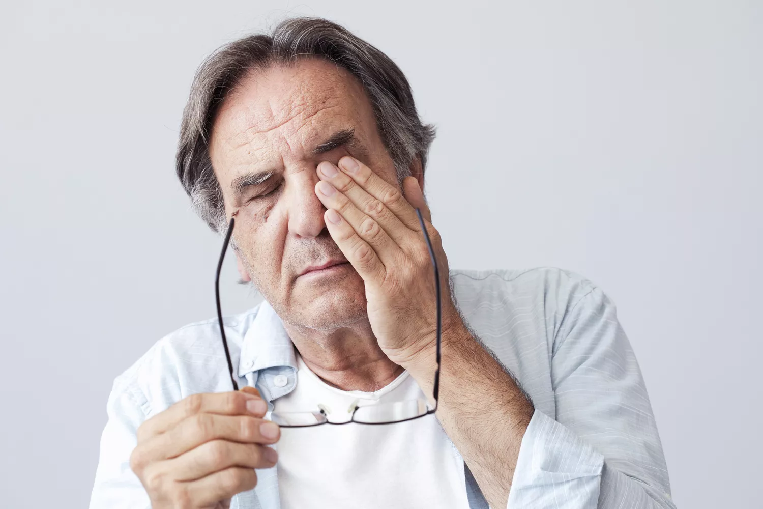 A person covering one eye with their hand looking concerned or confused.