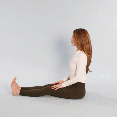 A person performing a seated spinal stretch by rotating their torso to relieve sciatic nerve pressure.