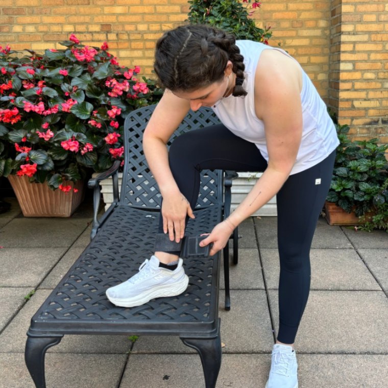 A woman outdoors wrapping a black Bala Bangle securely around her ankle.