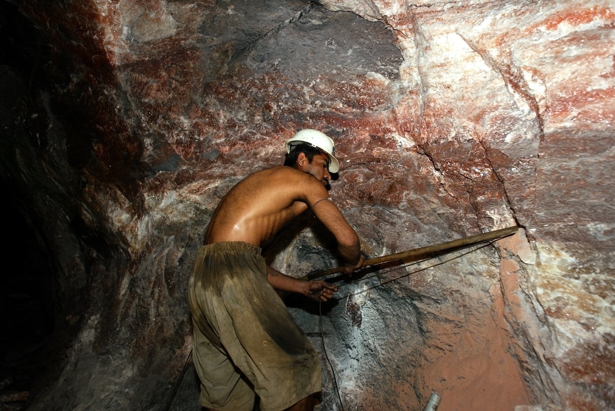 A miner working in a pink salt cavern extracting minerals.