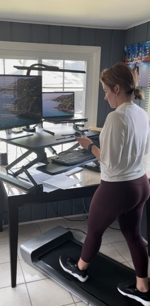 A compact folding walking pad positioned perfectly under a modern standing desk.