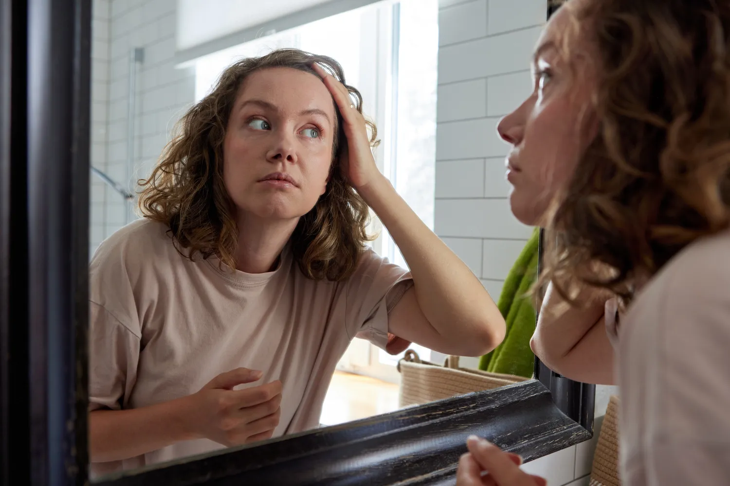A woman in a bathroom setting performing a self-care routine, representing the context of sleep preparation.