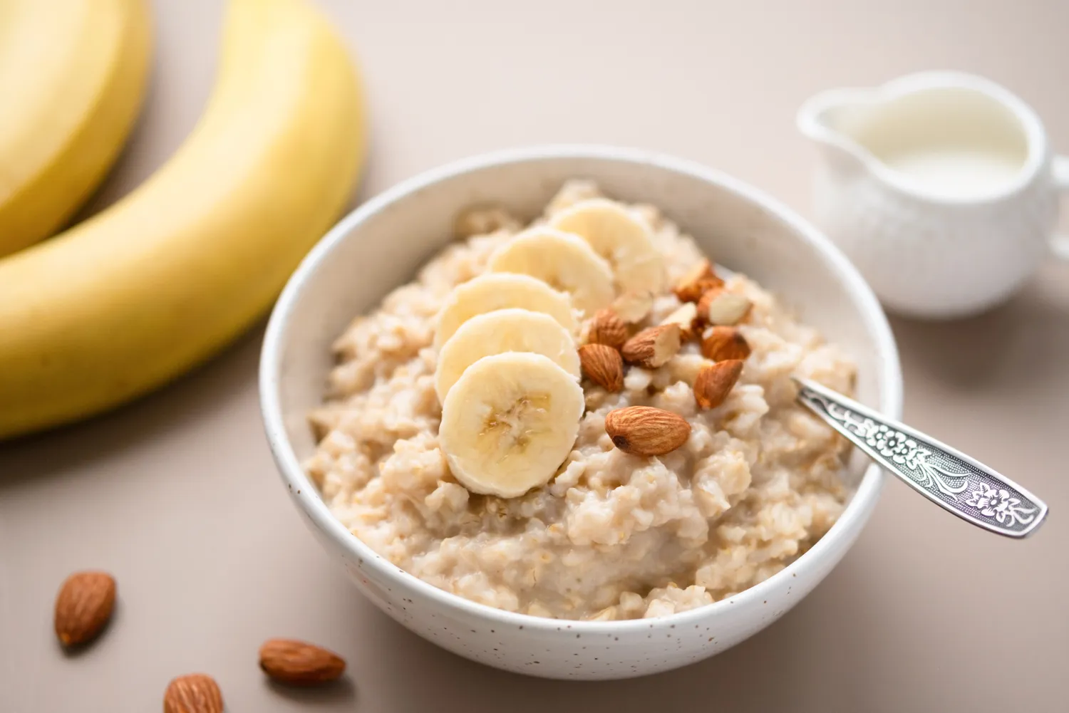 A bowl of oatmeal topped with banana slices and nuts.