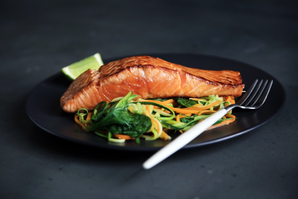 A grilled salmon fillet served with fresh lemon and green herbs.