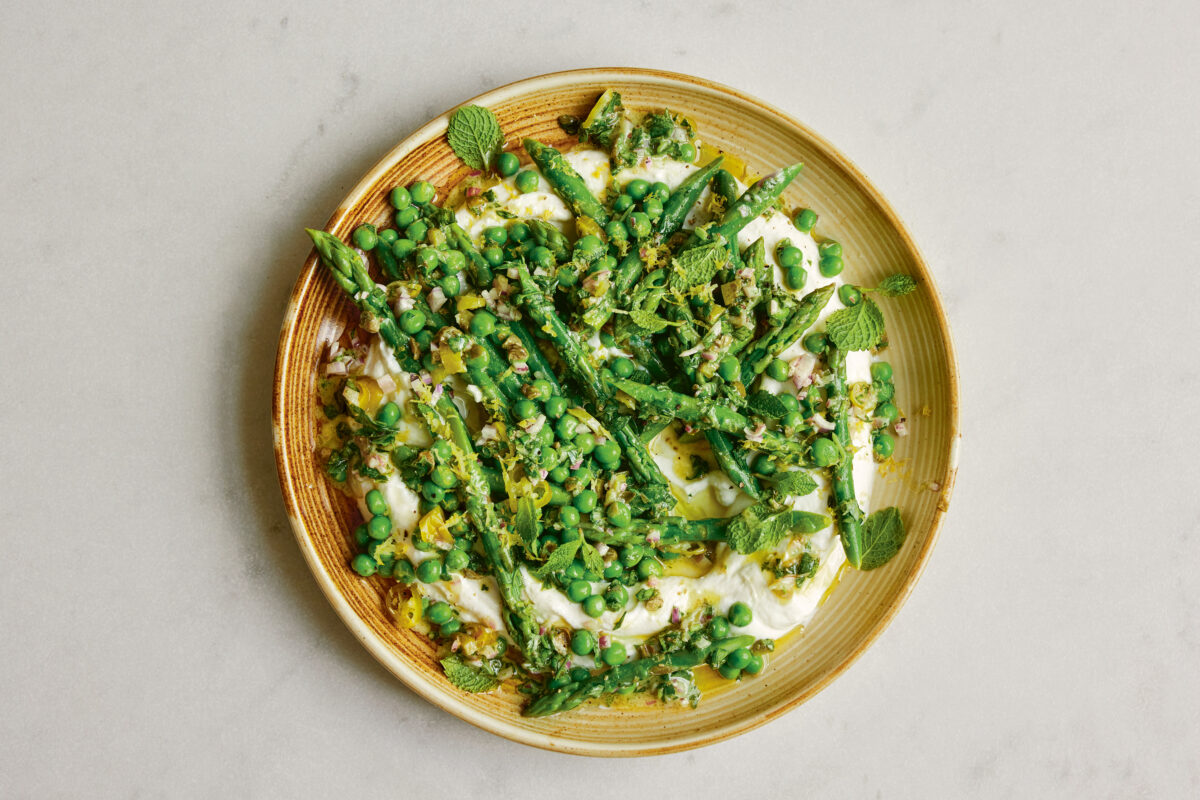 Raw fresh ingredients including asparagus, lime, and greens on a wooden background.