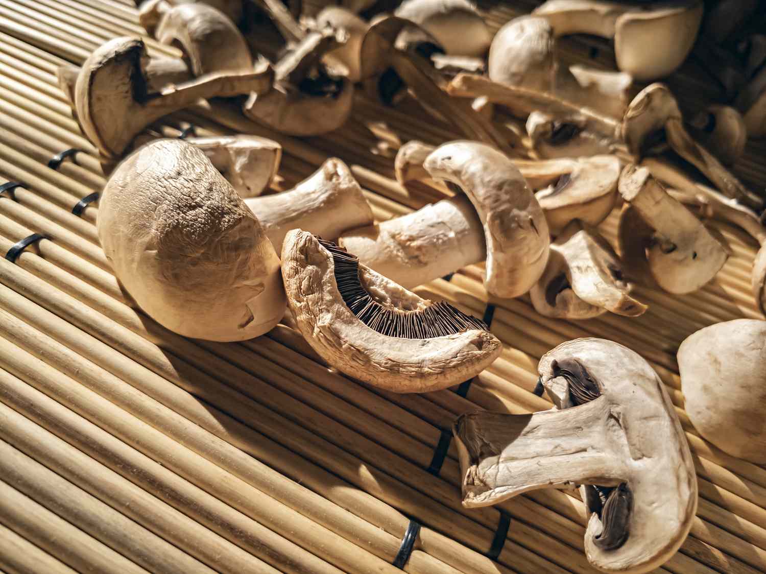 Sliced and whole mushrooms on a bamboo surface.