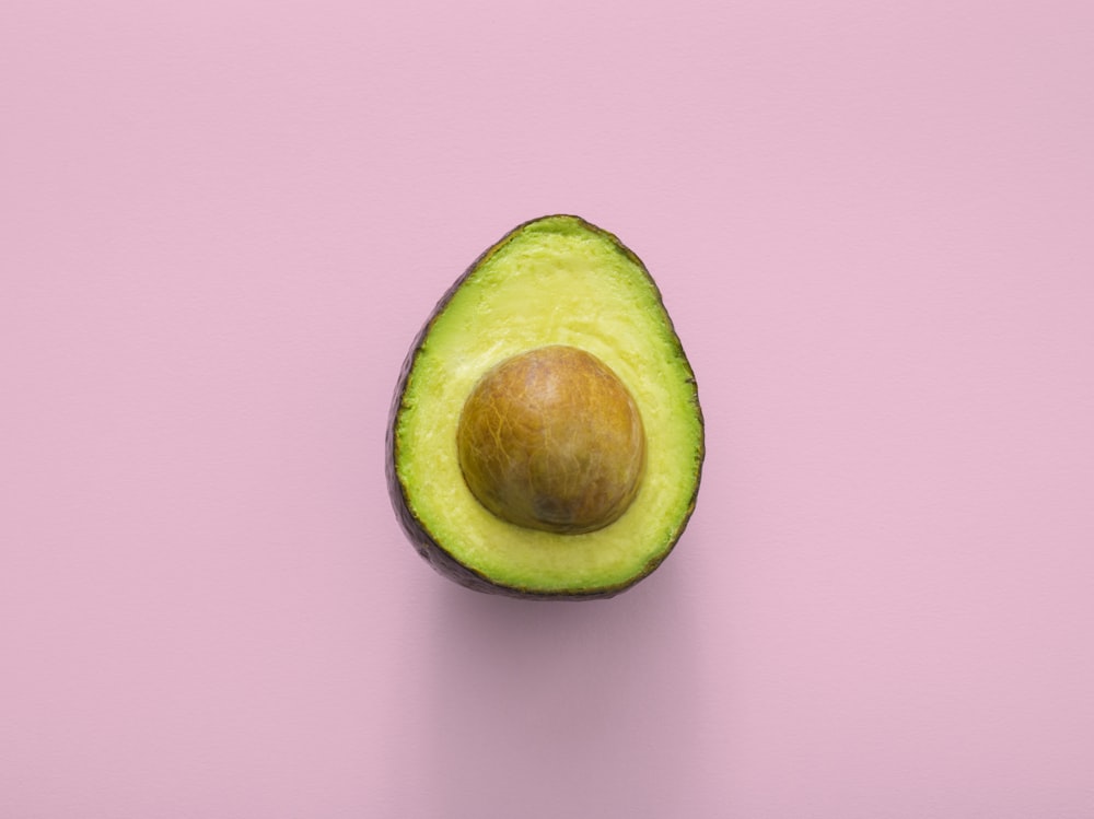 Sliced fresh avocado next to a clear glass bottle of olive oil.