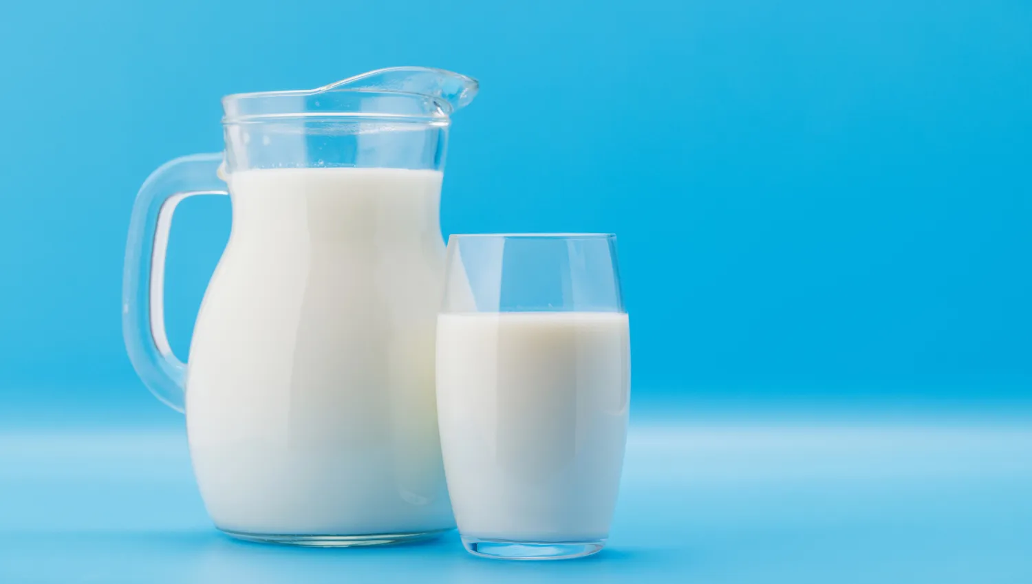 A glass of cold white milk on a neutral background.