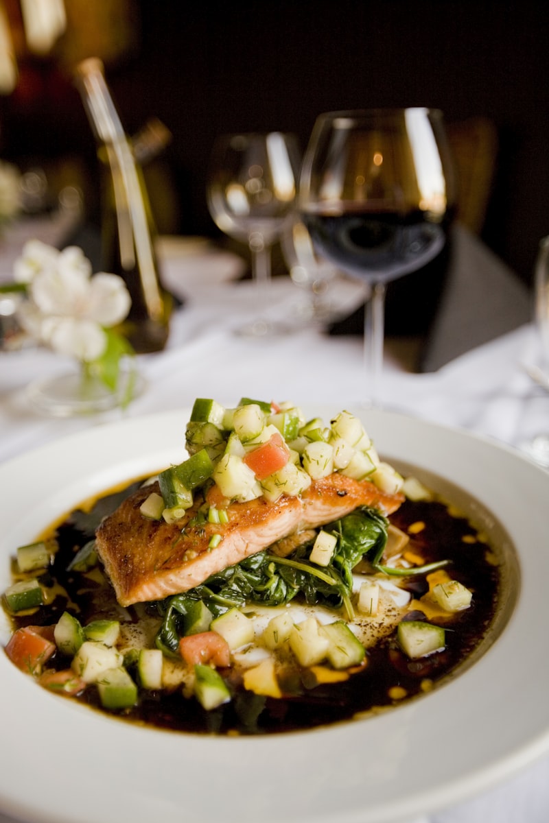 A plate of grilled salmon served with fresh herbs and colorful vegetables.