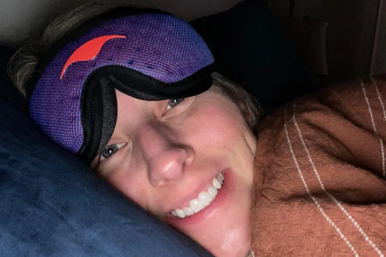 A shift worker wearing a blue sleep mask for daytime rest.