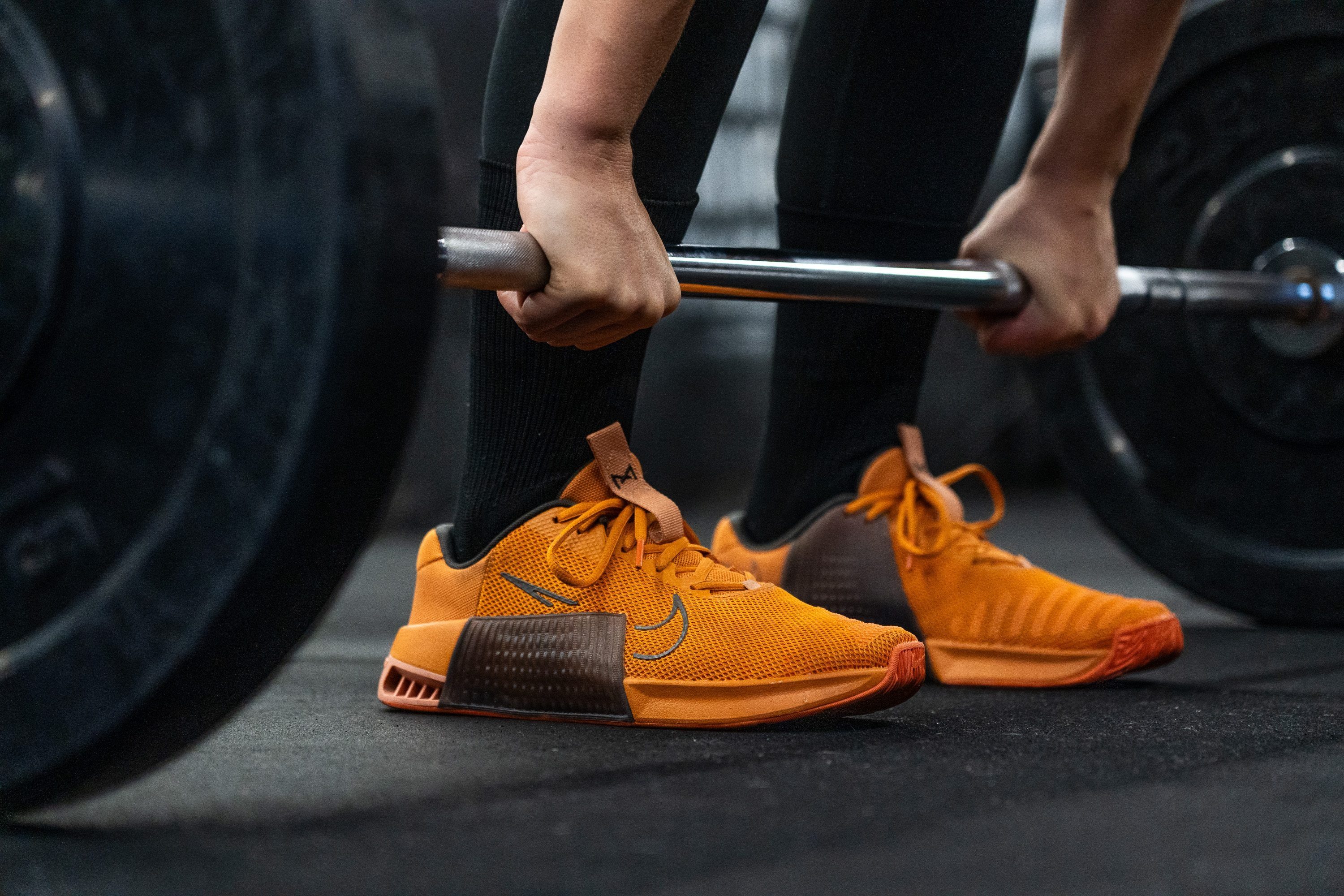 A person wearing performance trainers performing a heavy barbell squat in a gym.