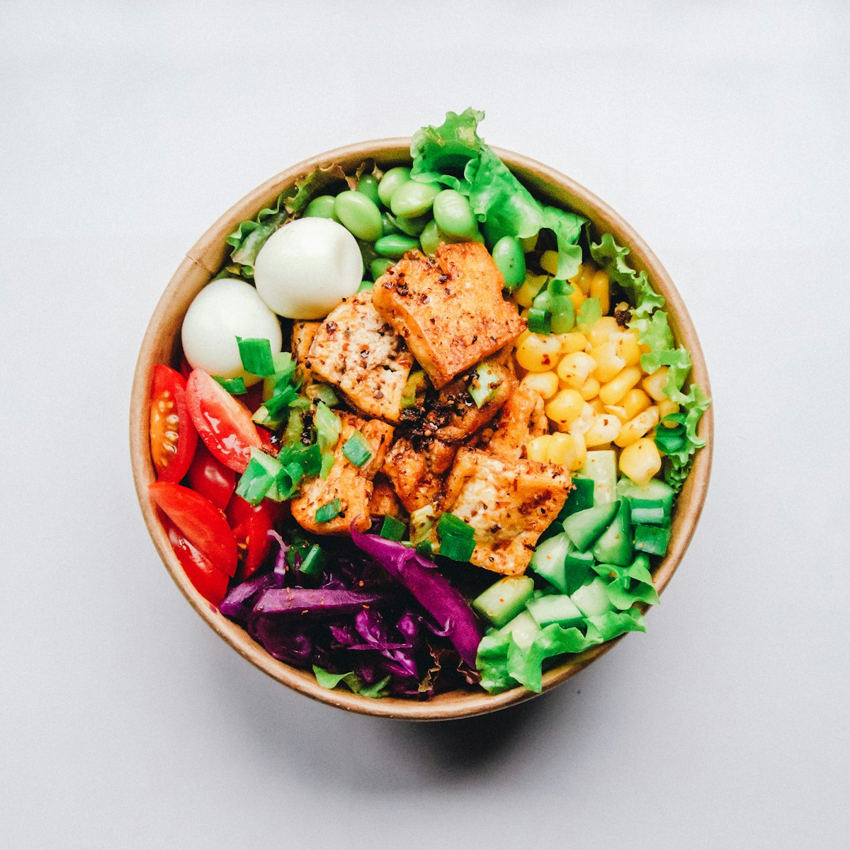 A side-by-side comparison of fresh raw vegetables and industrial packaged food containers.