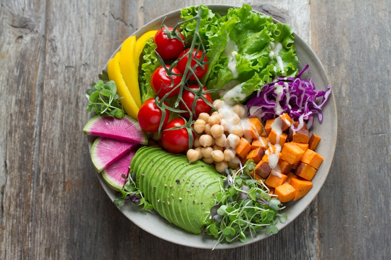 A bowl filled with a variety of fresh colorful vegetables and whole grains.