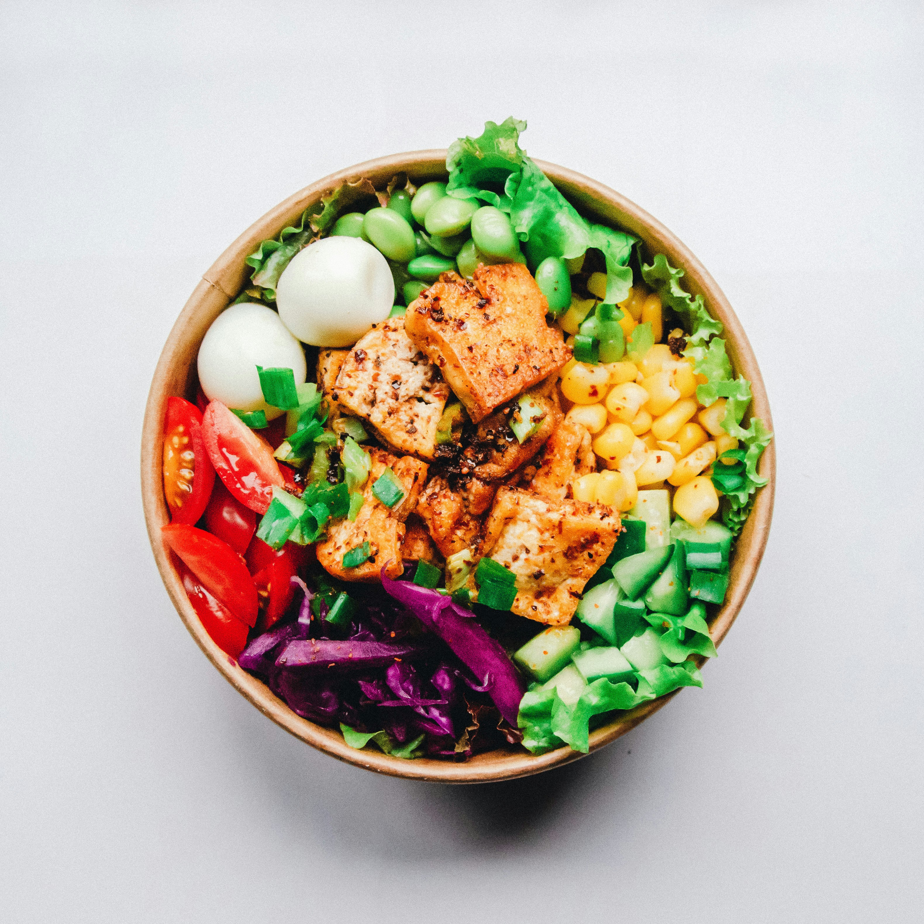 A bowl of cooked lentils garnished with fresh vegetables.