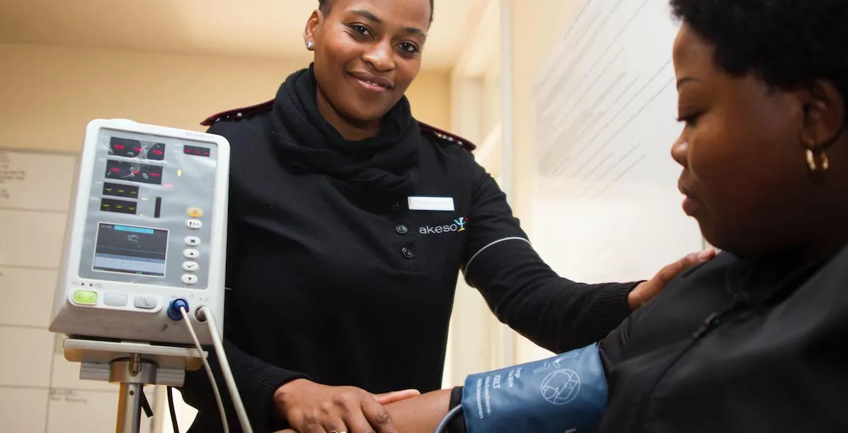 A woman in a clinical setting speaking with a doctor about her digestive symptoms.