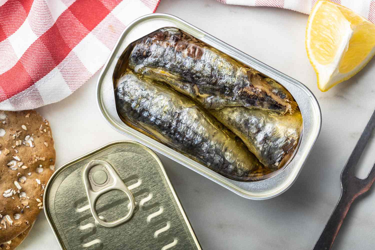 An overhead view of several canned sardines in tin containers on a wooden kitchen surface.