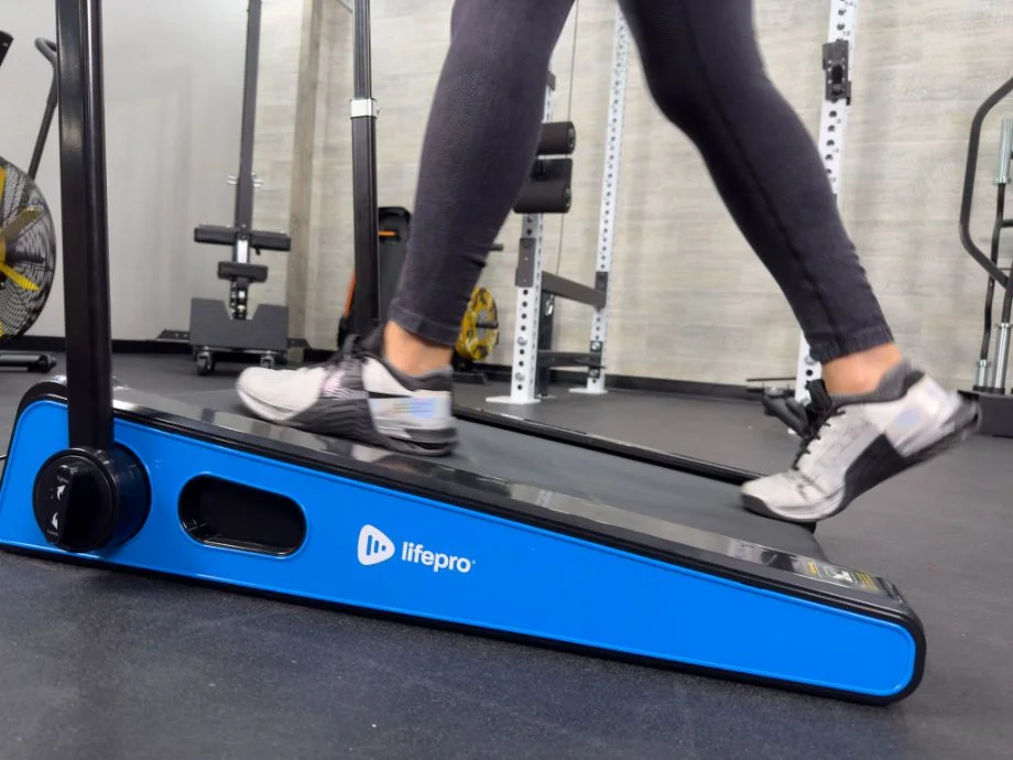 Low-angle close-up of athletic shoes walking on a cushioned treadmill belt.