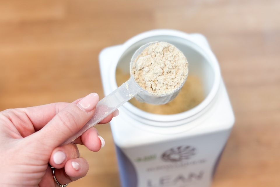 A container of SunWarrior Lean Superfood Shake on a kitchen counter.