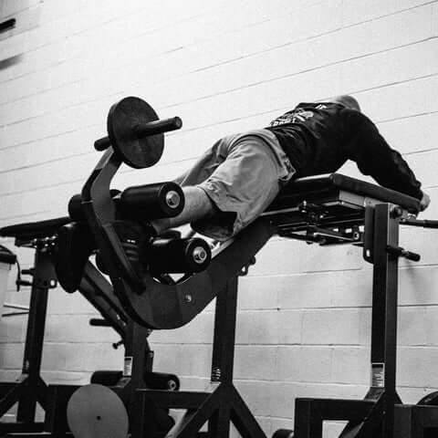 A lifter performing the exercise on a bent pendulum reverse hyper machine.