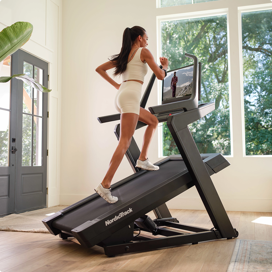Close-up of a treadmill set to a steep incline with a person walking at a steady pace.